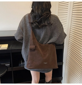 Deep brown suede tote bag worn over the shoulder showing large capacity and soft texture
