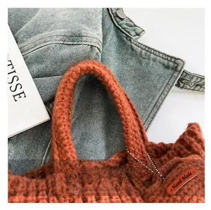Detail view of brick red knit handbag showing thick texture and Hand Made leather tag