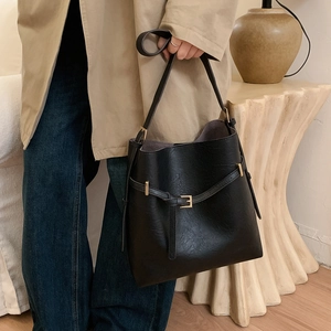 Detail of minimalist black bucket bag with lychee texture and gold buckle decoration