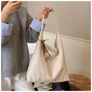 Detail view of large cream tote bag with soft PU leather and coffee tassel charm