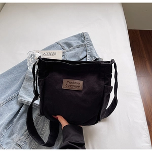 Detail of black canvas tote bag with adjustable strap and leather fashion label