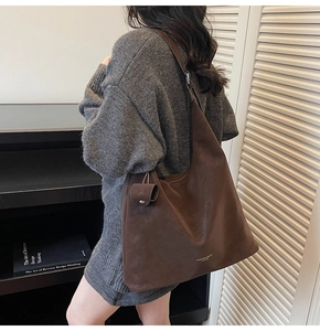 Detail of dark brown matte hobo bag worn as underarm shoulder bag with coin pouch