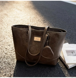 Detail of dark brown faux leather tote with cat embossed patterns and heart charm