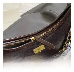 Close-up of a brown quilted bag featuring a golden twist lock and metal chain strap