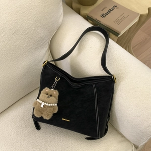Detail of black matte leather hobo bag with contrast stitching and bear charm