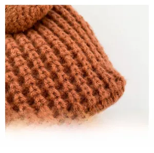 Detail shot of caramel brown chunky knit fabric showing 3D checkered texture and soft finish