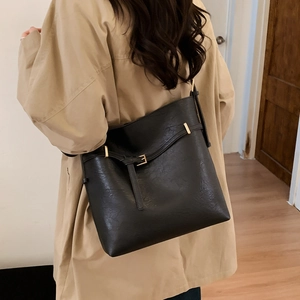 Model wearing a black vintage bucket bag with gold buckle over a beige trench coat
