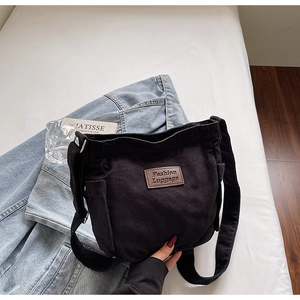 Detail of black canvas tote bag with adjustable strap and leather fashion label