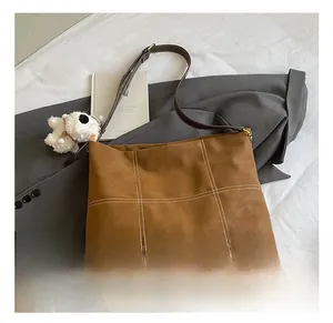 Détail du sac cabas marron avec coutures à carreaux blancs et fines anses en cuir
