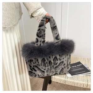 Close-up of grey leopard print plush handbag with dark faux fur trim on a woven chair