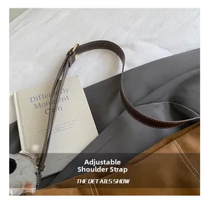 Détail de la bandoulière réglable en cuir marron avec boucle dorée et petit charme