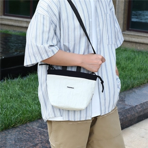 Outdoor shot of a minimalist black and white nylon crossbody bag with drawstring closure