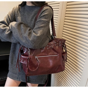 Détail latéral du grand sac cabas en cuir verni rouge foncé avec clous et poches