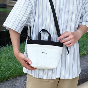 Outdoor model showing the mini crossbody nylon bag in cream with black straps