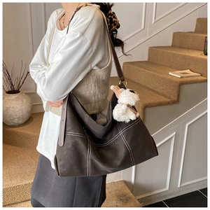 Détail du sac fourre-tout marron foncé avec surpiqûres blanches et charme chien en peluche