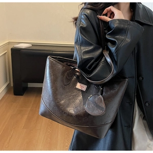 Detail of dark brown leather tote bag with embossed bear pattern and heart coin purse