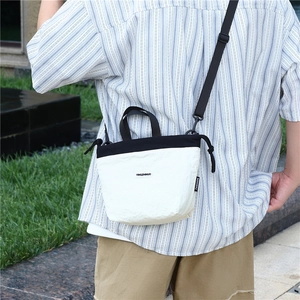Detail of a mini nylon crossbody bag featuring contrast colors and adjustable strap