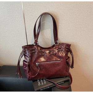 Détail du sac cabas rouge foncé avec fermetures éclair et poches à rivets latéraux