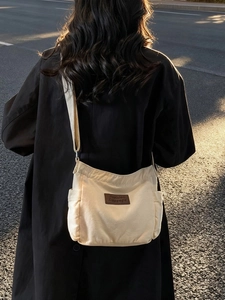 Minimalist beige canvas tote bag with brown leather label worn by a model in soft sunset light