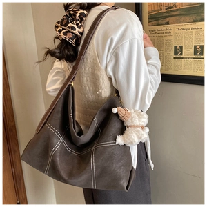 Détail du sac cabas vintage avec coutures contrastées et charm chien en peluche