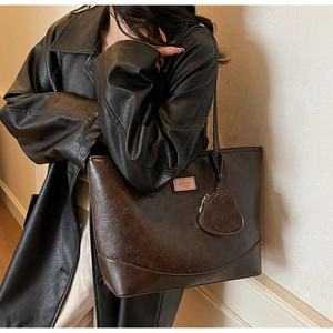Detail of dark brown tote bag with bear embossed pattern and heart shaped charm