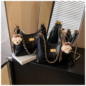 Detail of black quilted hobo bag with chunky gold chain and cute plush bear charm