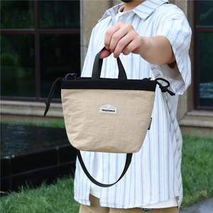 Detail of khaki and black nylon crossbody bag with adjustable strap and top handle