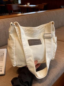 Chic beige canvas tote bag with adjustable strap and side pockets for daily fashion