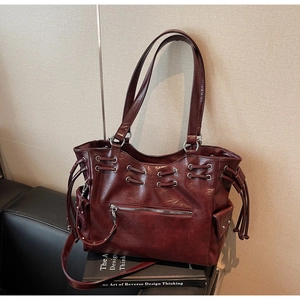 Détail du sac cabas bordeaux avec œillets métalliques, poche zippée et poches latérales