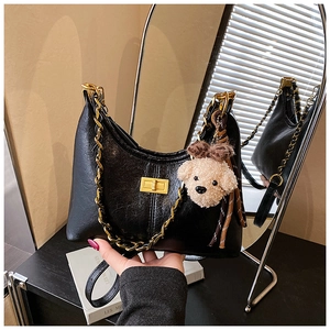 Detail view of black Boston style handbag with chunky gold chain and dog plush charm