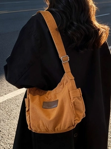 Brown canvas tote bag with adjustable shoulder strap shown in a city street setting