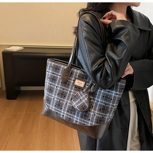 Detail of checkered tote bag featuring leather handles and heart-shaped coin purse attachment