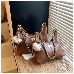 Detail of vintage brown crescent bag with gold chain strap and plush bear charm