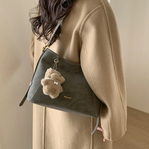 Detail of dark grey retro bucket bag with white contrast stitching and plush bear charm