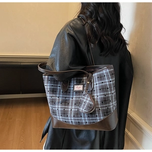 Detail of blue plaid tote bag with leather trim and star print on a model shoulder