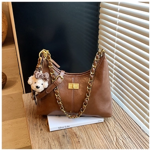 Close-up of brown quilted leather crossbody bag with gold chain and plush bear charm
