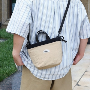 Close-up of beige nylon crossbody bag with adjustable strap and logo detail