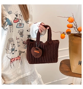 Detail of dark brown crochet handbag with handmade heart charm and leather logo tag