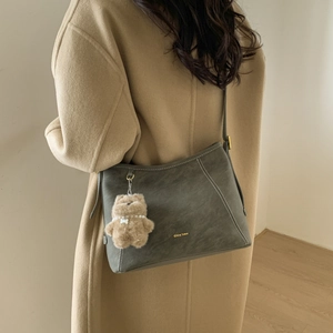 Detailed shot of retro bucket bag with decorative stitching and plush bear charm