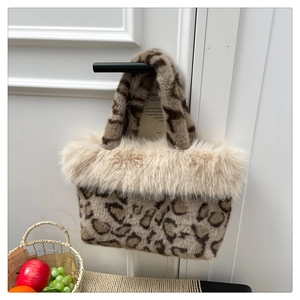 Detail of plush leopard print handbag with beige faux fur trim hanging on a door handle