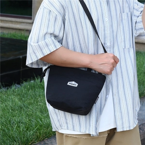 Detail of lightweight black nylon crossbody bag with silver logo and adjustable strap