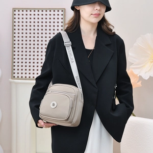 Detail einer beigen Umhängetasche mit Multi-Taschen und Logogurt am Model