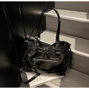 Détail du sac cabas noir brillant avec fermetures éclair argentées et rivets métalliques