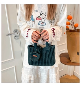 Detail of dark green crochet handbag featuring handmade heart charm and chunky knit texture