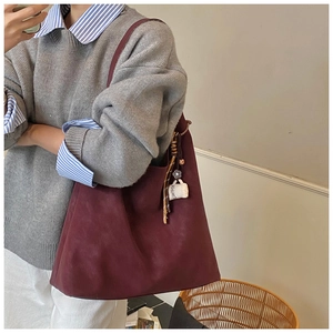 Close-up of burgundy suede tote bag with a coffee cup pendant and minimalist design
