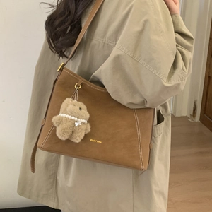 Brown suede bucket bag detail with contrast stitching and plush bear charm accessory