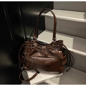 Gros plan sur un sac cabas en cuir huilé marron avec fermetures éclair argentées et poches