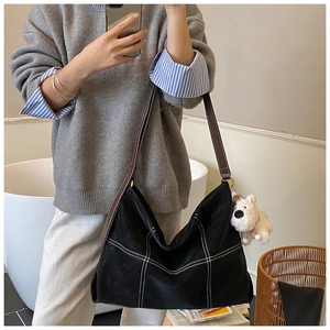 Selfie miroir montrant un grand sac fourre-tout noir avec surpiqûres et breloque peluche