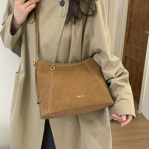 Detail of vintage brown bucket bag featuring contrast white stitching and gold hardware