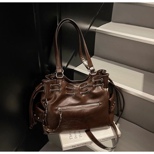 Détail du sac cabas en cuir marron foncé avec texture à cordon et accents en métal argenté